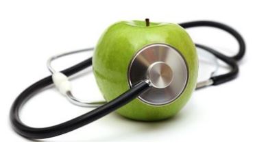 Beschrijving afbeelding: een stethoscoop kleeft centraal op een blinkend groene Granny Smith appel.