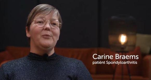 Beschrijving afbeelding: close-up van een gefocuste Karine. Als bijschrift lezen we Carine Braems patiënt Spondyloarthritis.